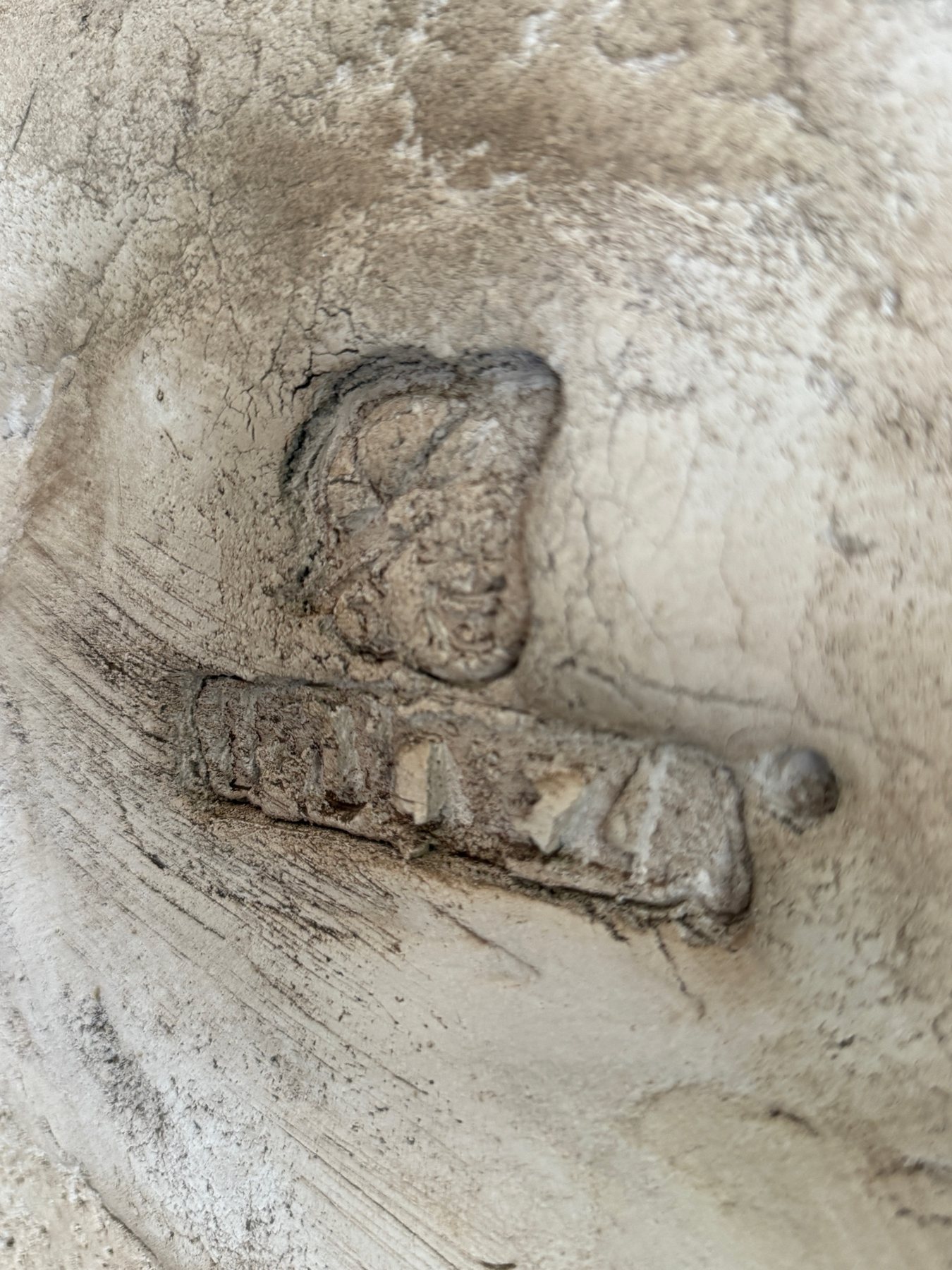 Détail d'un emblème IMULTEZA sculpté dans une surface minérale.